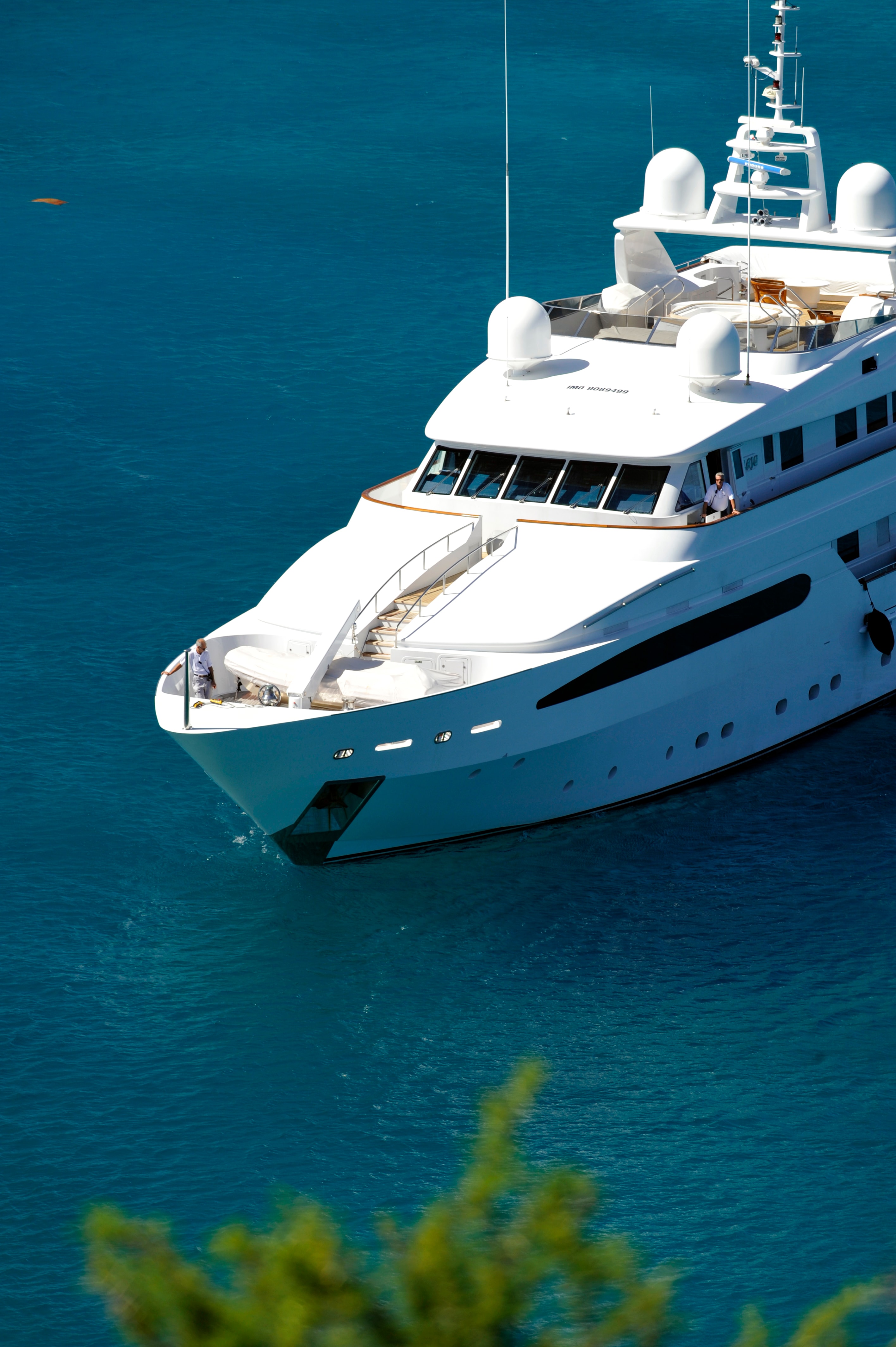 A white megayacht’s bow, bridge and upper decks against deep blue water