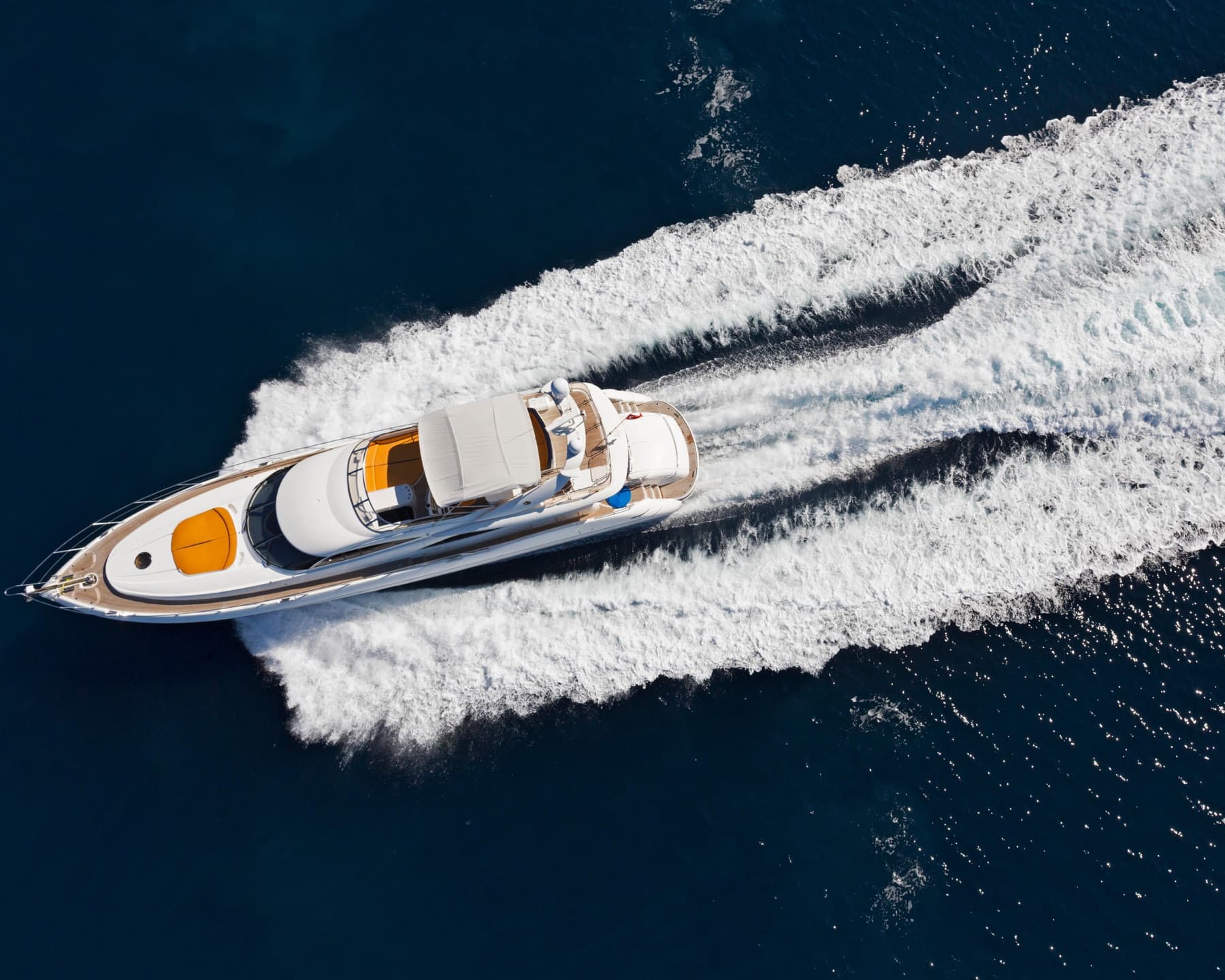 Motor yacht and wake seen from above on dark blue water