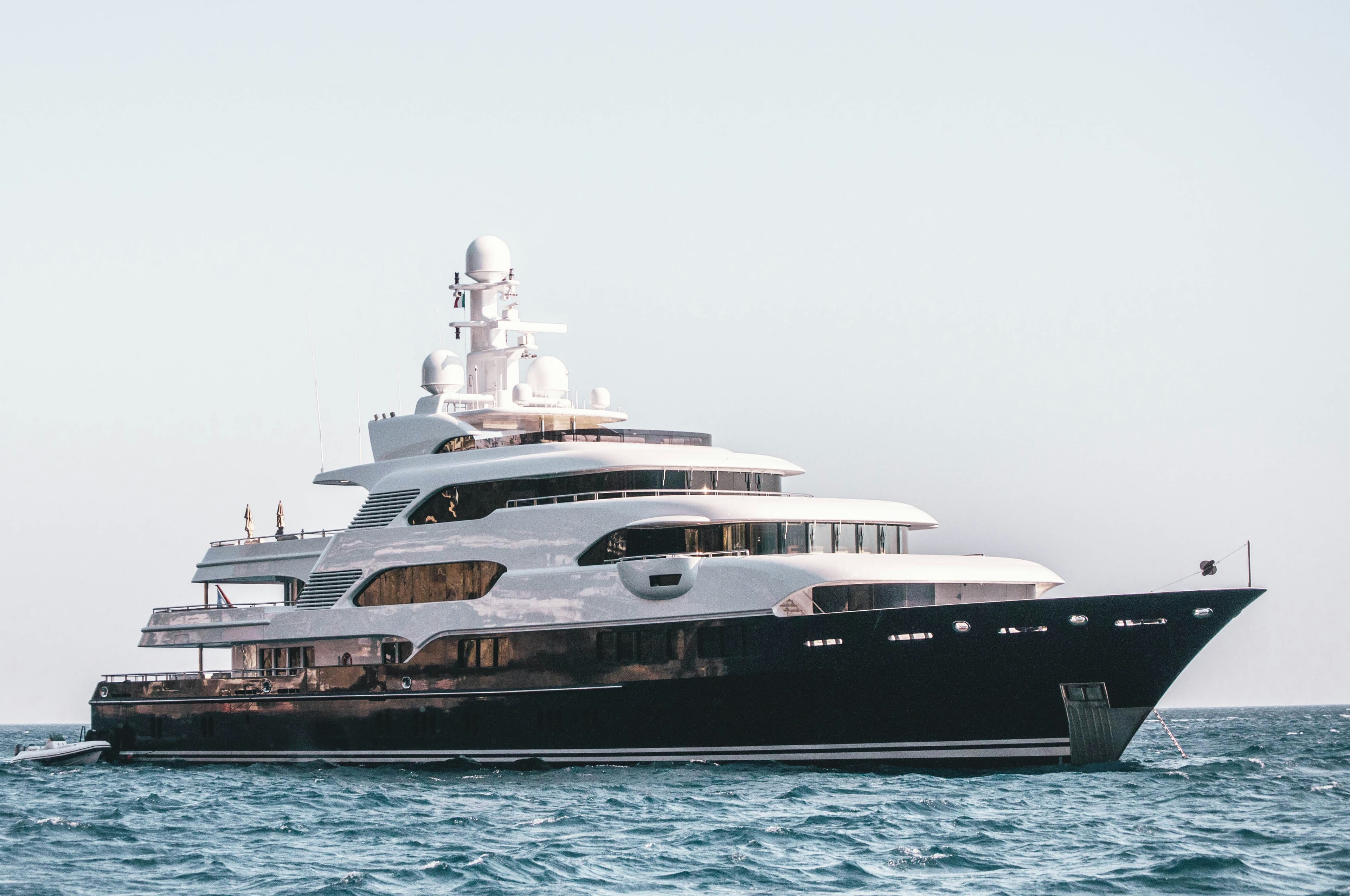 Large motor yacht with a dark hull at anchor on open water